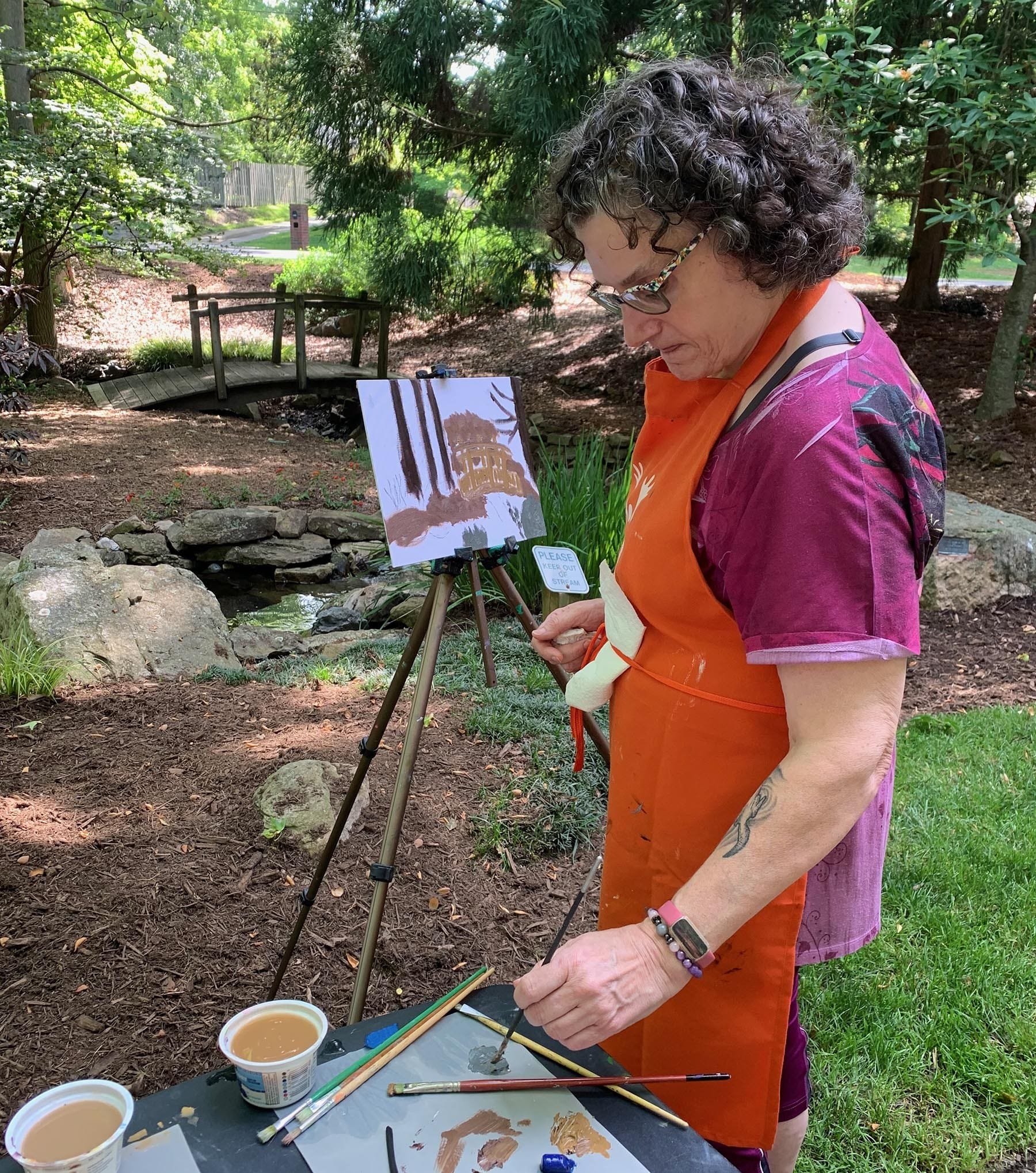 woman painting at easel outside