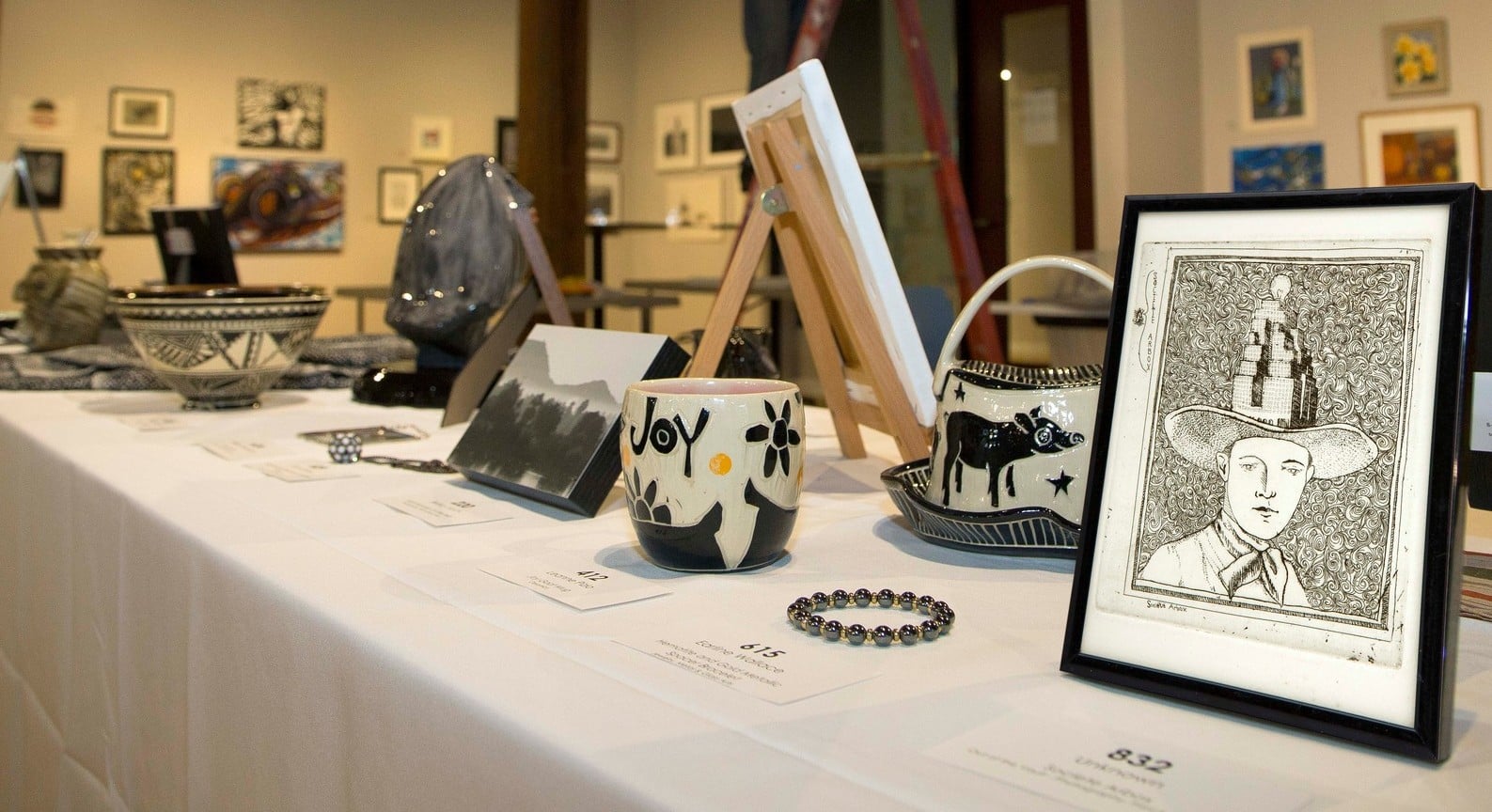 pieces of art on a long table - pottery, framed drawing